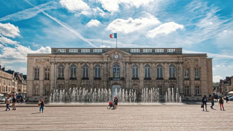 Hôtel de ville avec fontaines et drapeau français.